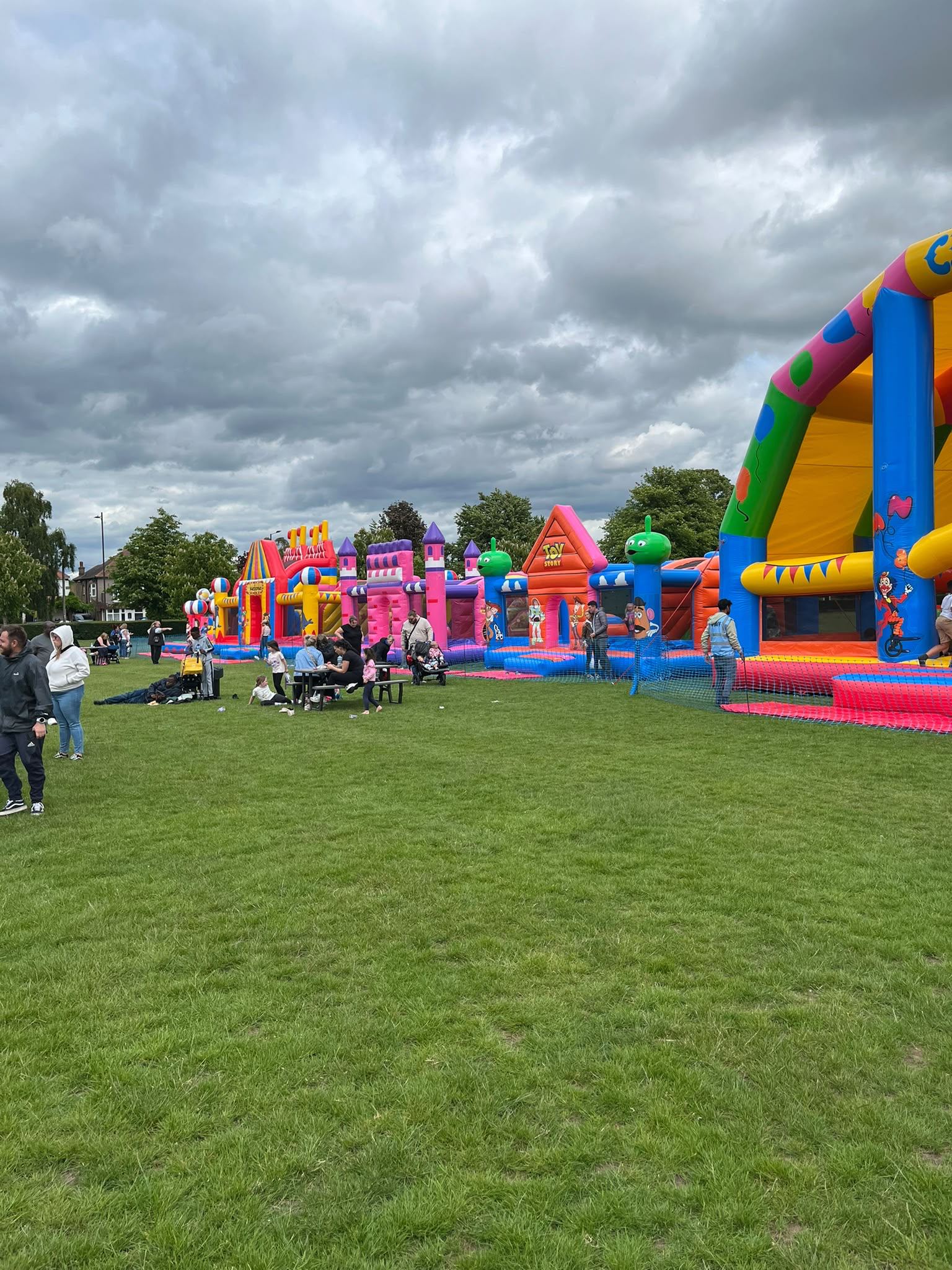 A row of large themed inflatables including a circus arch and castle-style bounce houses set up on a sunny playing field