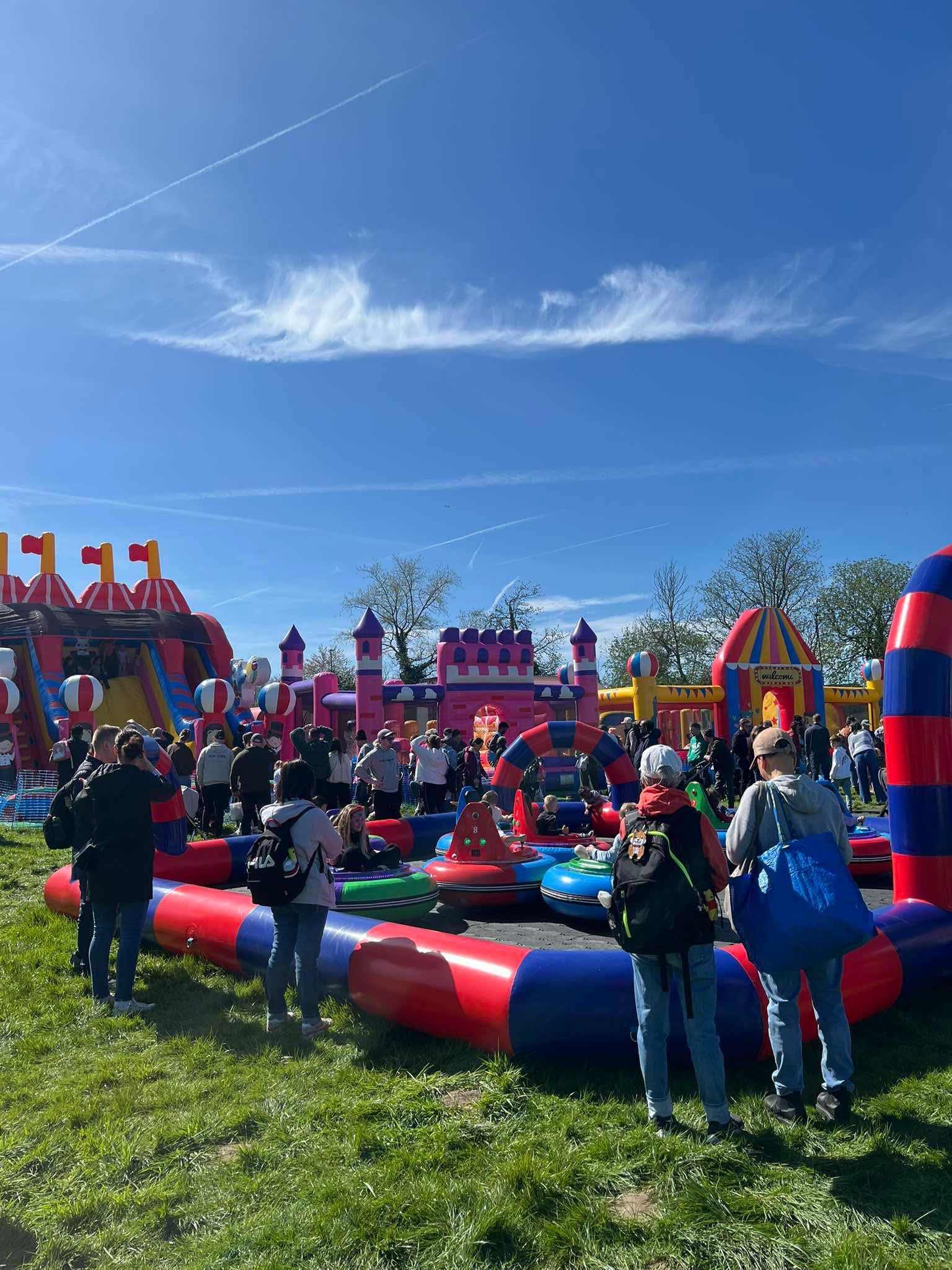 A large crowd of families among mega inflatables, an inflatable bumper car track and fairground rides at a busy Bonds Leisure event
